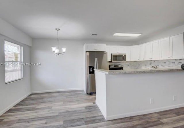 kitchen with appliances with stainless steel finishes, light hardwood / wood-style flooring, white cabinetry, and hanging light fixtures