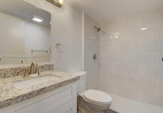 bathroom with a tile shower, vanity, and toilet