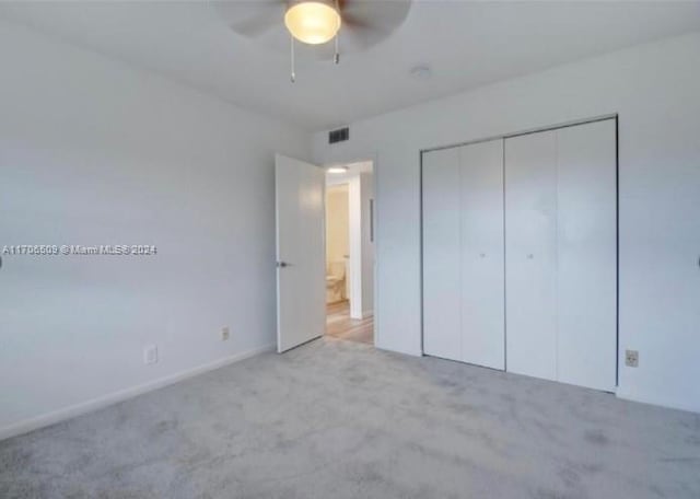 unfurnished bedroom featuring ceiling fan, a closet, and light colored carpet