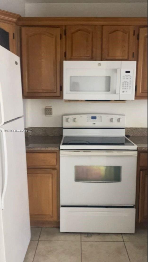 kitchen with light tile patterned floors and white appliances