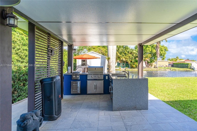 view of patio / terrace featuring a grill, sink, a water view, and exterior kitchen