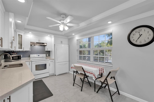 kitchen featuring white appliances, a tray ceiling, ceiling fan, sink, and white cabinetry