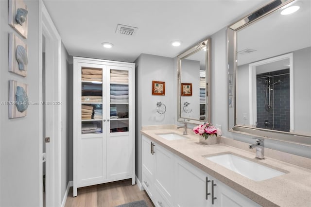 bathroom with a tile shower, vanity, and wood-type flooring