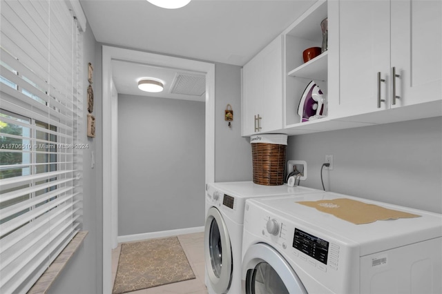 laundry area with washer and dryer, light tile patterned flooring, and cabinets