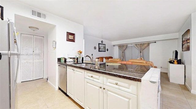 kitchen with stainless steel appliances, visible vents, white cabinets, a sink, and dark stone countertops