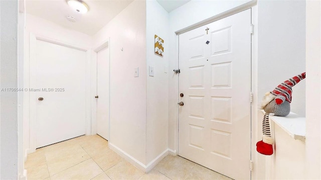 foyer featuring light tile patterned flooring and baseboards