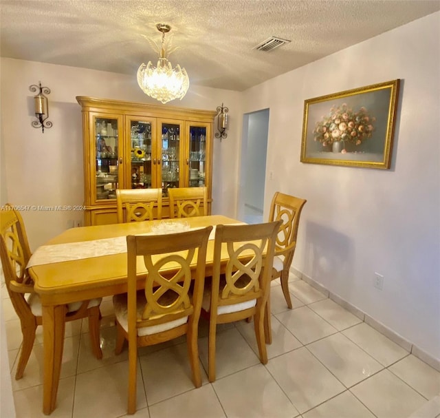 tiled dining area with a notable chandelier and a textured ceiling