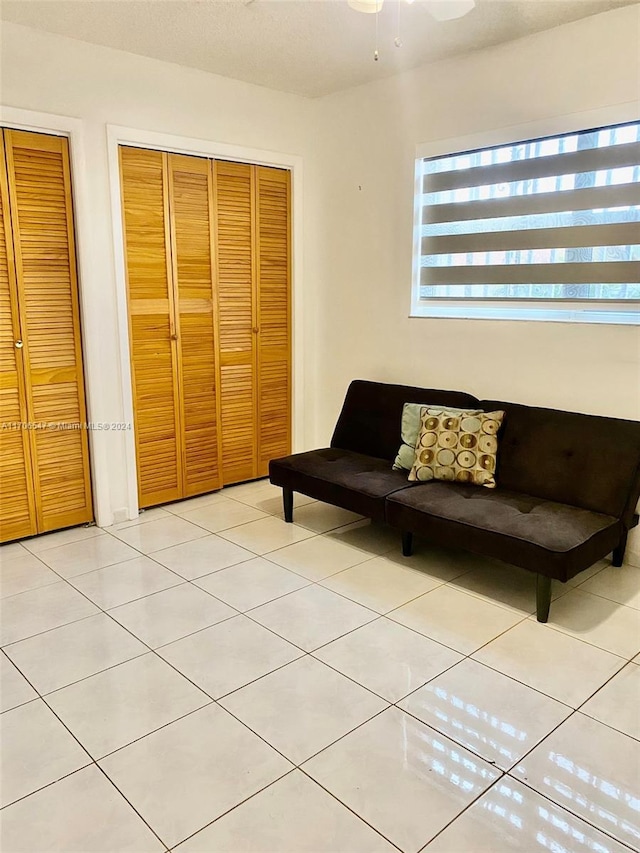 living area with ceiling fan and light tile patterned flooring