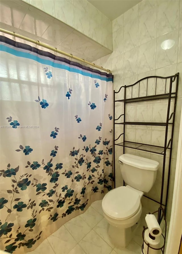 bathroom with a shower with shower curtain, toilet, and tile walls