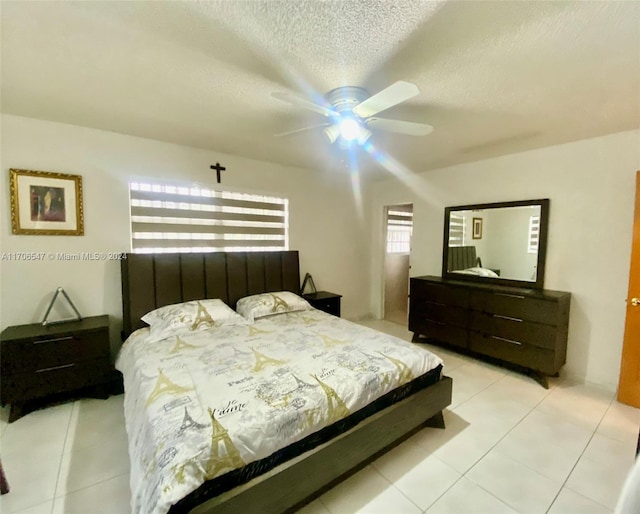 bedroom featuring light tile patterned floors, a textured ceiling, and ceiling fan