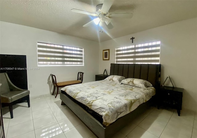 bedroom featuring ceiling fan, light tile patterned floors, and a textured ceiling