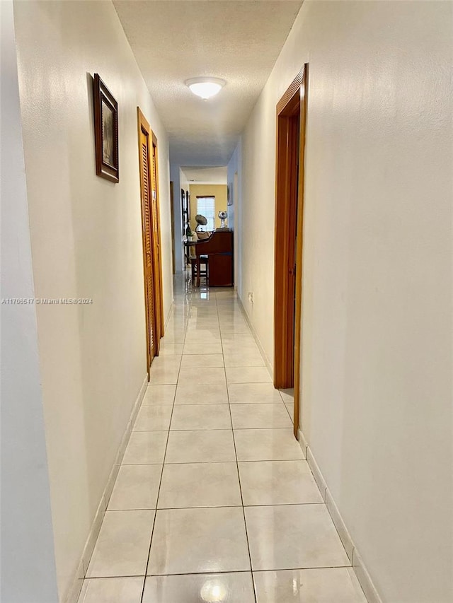 corridor with light tile patterned flooring and a textured ceiling