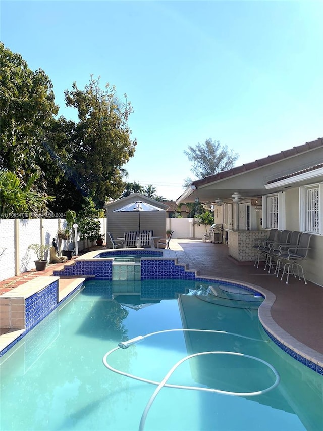 view of pool with a patio area, an in ground hot tub, a bar, and pool water feature