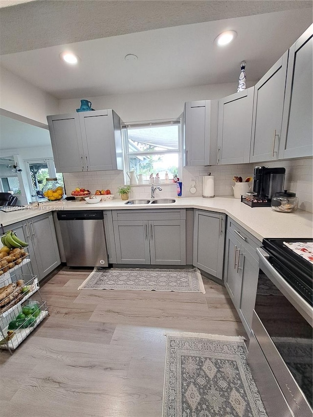 kitchen with gray cabinets, light hardwood / wood-style floors, sink, and stainless steel appliances