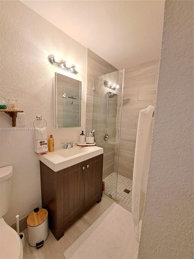 bathroom with tile patterned flooring, a textured ceiling, toilet, a shower with door, and vanity