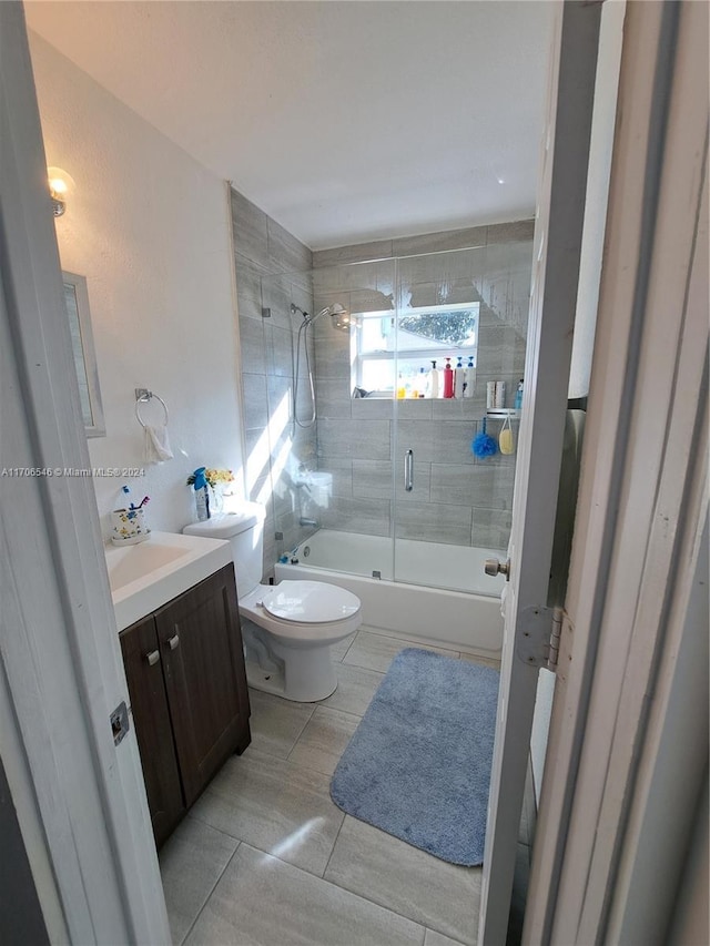 full bathroom featuring combined bath / shower with glass door, vanity, and toilet