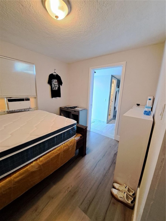 bedroom featuring wood-type flooring, a textured ceiling, and cooling unit