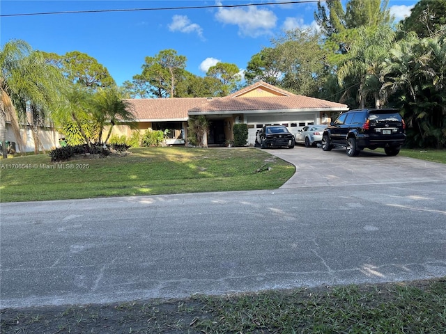 view of front of home with an attached garage, a tiled roof, a front lawn, and concrete driveway