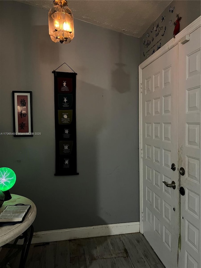 foyer with wood finished floors, baseboards, and a textured ceiling