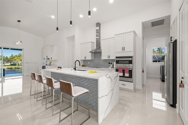 kitchen featuring pendant lighting, wall chimney range hood, stainless steel appliances, and a wealth of natural light