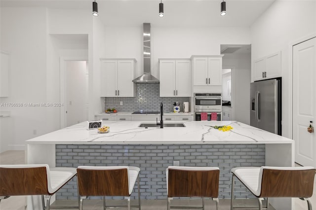 kitchen with white cabinetry, sink, wall chimney exhaust hood, stainless steel appliances, and light stone counters