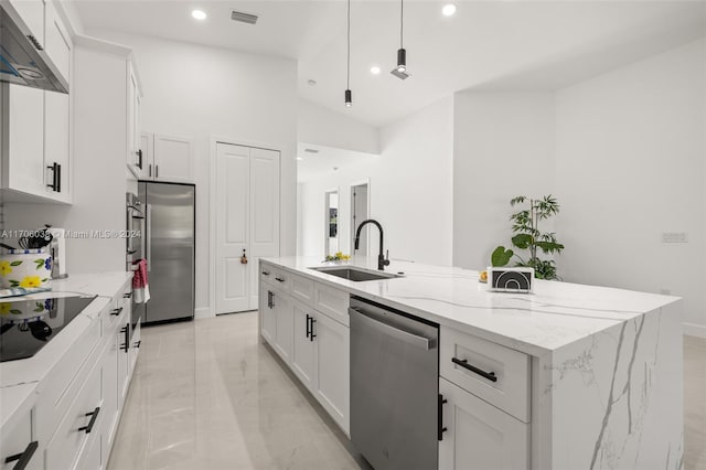 kitchen with white cabinets, appliances with stainless steel finishes, a kitchen island with sink, and sink