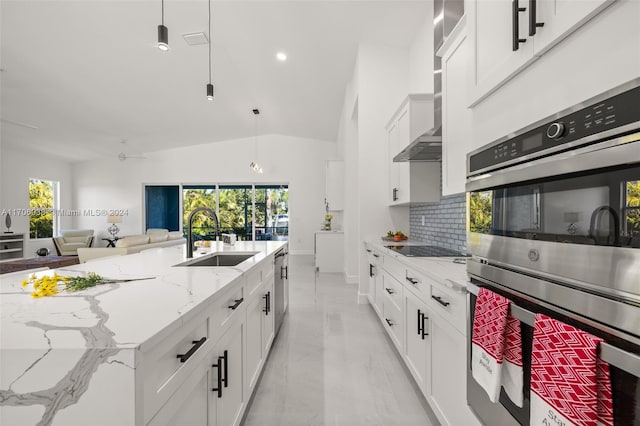 kitchen with stainless steel appliances, sink, pendant lighting, white cabinetry, and lofted ceiling