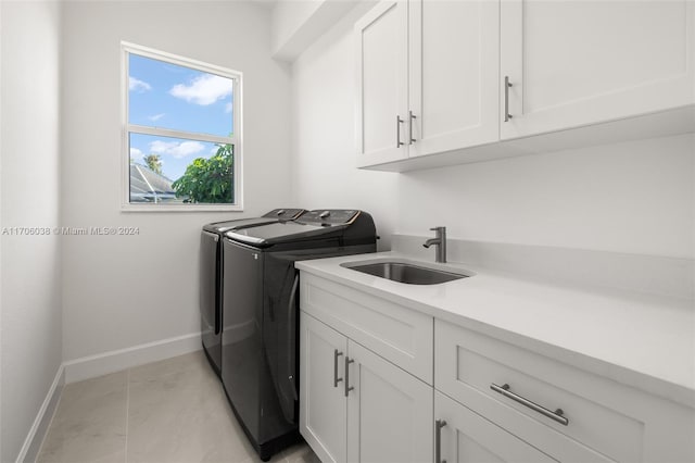 clothes washing area with washer and dryer, cabinets, and sink