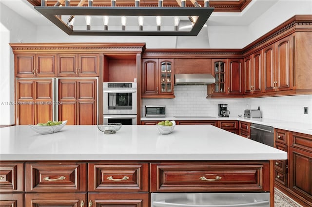 kitchen featuring stainless steel appliances, decorative backsplash, a center island, and exhaust hood