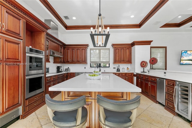 kitchen featuring stainless steel double oven, a raised ceiling, pendant lighting, wine cooler, and a breakfast bar area