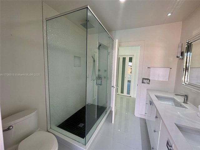 bathroom featuring tile patterned floors, vanity, toilet, and a shower with door