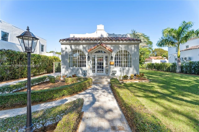 mediterranean / spanish-style house featuring french doors, a front yard, a tile roof, and stucco siding