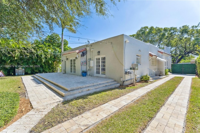 view of front of property with stucco siding, fence, and french doors