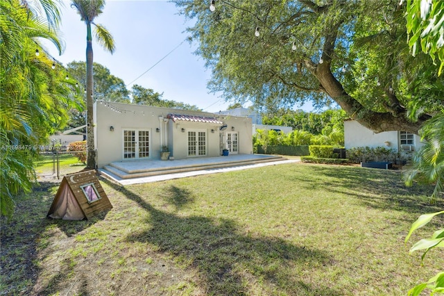 back of house with french doors, stucco siding, a lawn, a gate, and fence