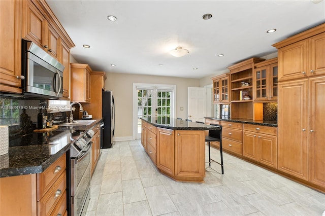 kitchen with stainless steel appliances, a center island, brown cabinetry, and a kitchen bar