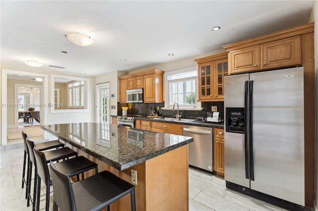 kitchen featuring a center island, a kitchen breakfast bar, sink, decorative backsplash, and appliances with stainless steel finishes