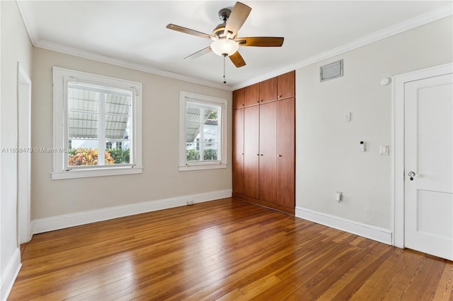 unfurnished bedroom with ceiling fan, wood-type flooring, and ornamental molding