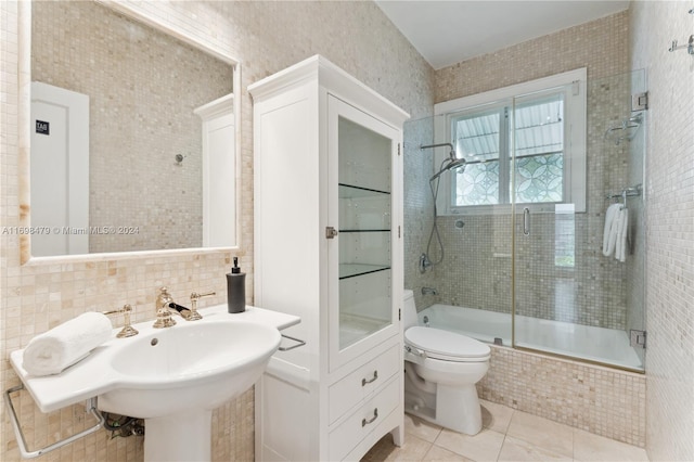 bathroom with tile patterned floors, decorative backsplash, toilet, enclosed tub / shower combo, and tile walls