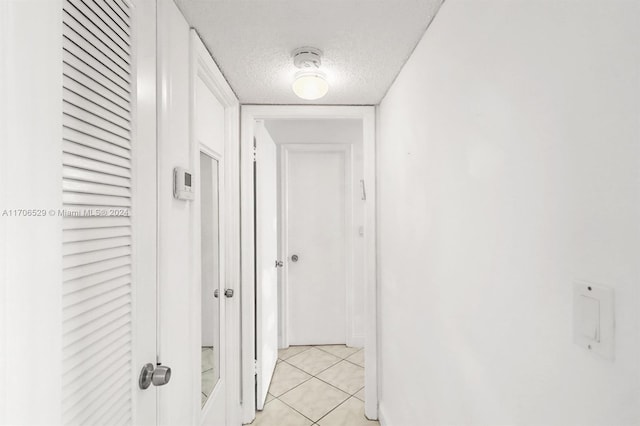 hall featuring light tile patterned floors and a textured ceiling