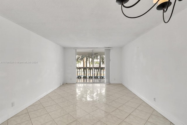 tiled spare room featuring a textured ceiling and ceiling fan