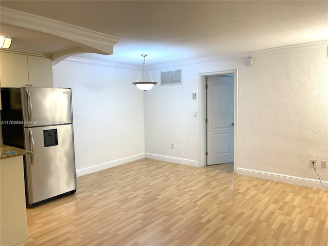 kitchen with ornamental molding, decorative light fixtures, light hardwood / wood-style flooring, dark stone countertops, and stainless steel refrigerator