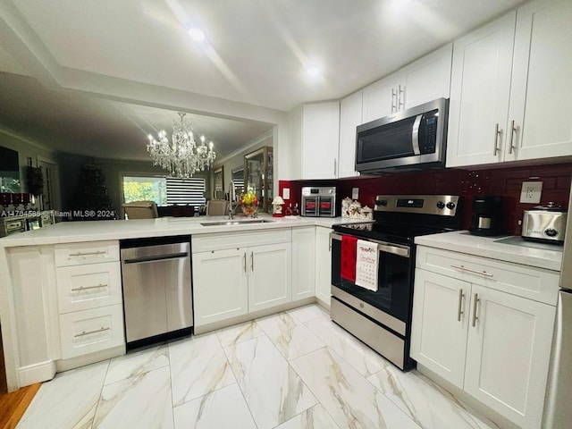 kitchen featuring an inviting chandelier, white cabinets, sink, decorative backsplash, and appliances with stainless steel finishes