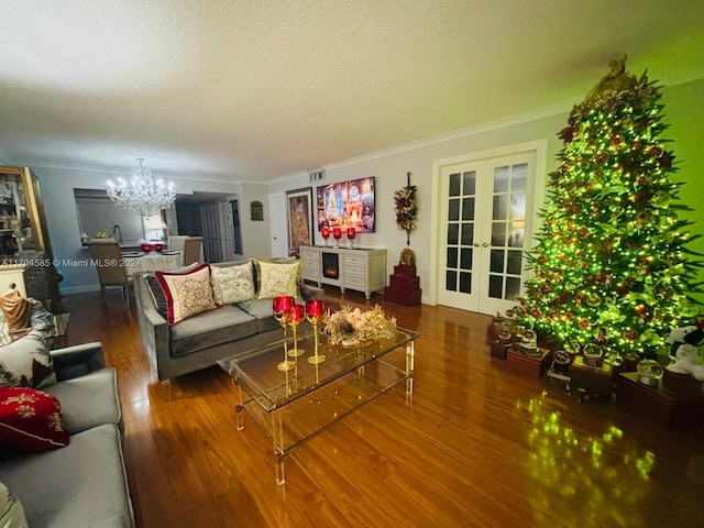 living room with french doors, crown molding, a textured ceiling, a notable chandelier, and dark hardwood / wood-style flooring