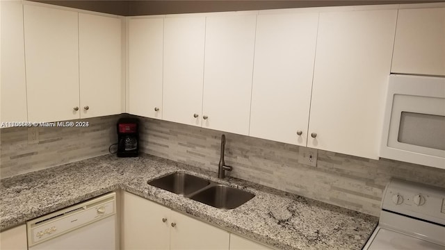 kitchen with dishwasher, stove, white cabinets, sink, and light stone counters