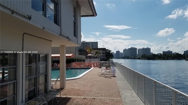 view of swimming pool with a patio area and a water view