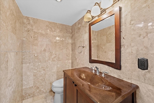 bathroom featuring tile patterned floors, vanity, toilet, and tile walls