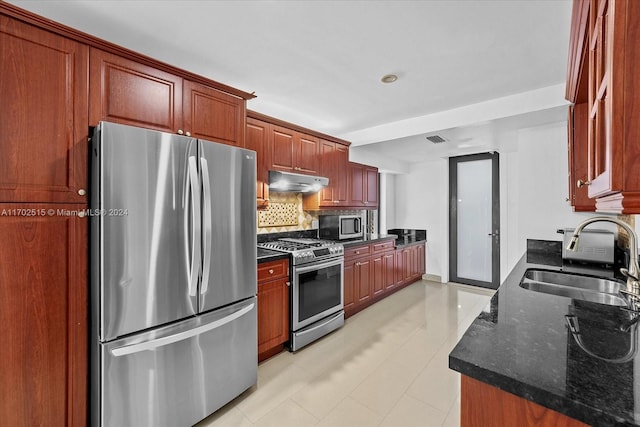 kitchen featuring backsplash, dark stone counters, sink, appliances with stainless steel finishes, and light tile patterned flooring