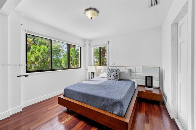 bedroom with multiple windows and dark hardwood / wood-style floors