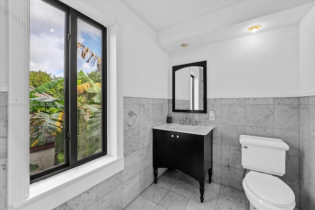 bathroom featuring vanity, toilet, and tile walls