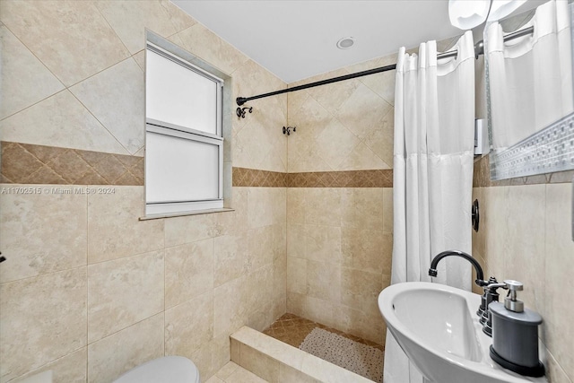 bathroom with toilet, curtained shower, sink, and tile walls